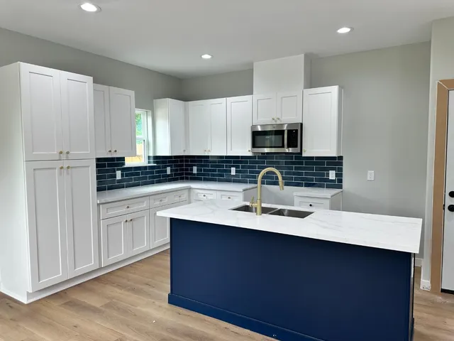 a kitchen with stainless steel appliances granite countertop a sink a stove a refrigerator a microwave and island with wooden floor