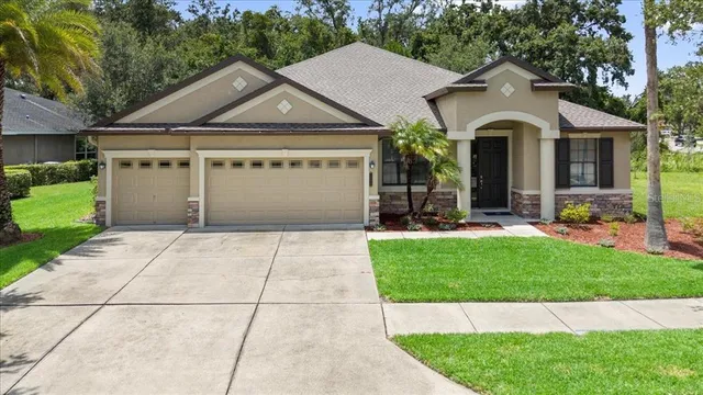 a view of a white house with a yard plants and large tree