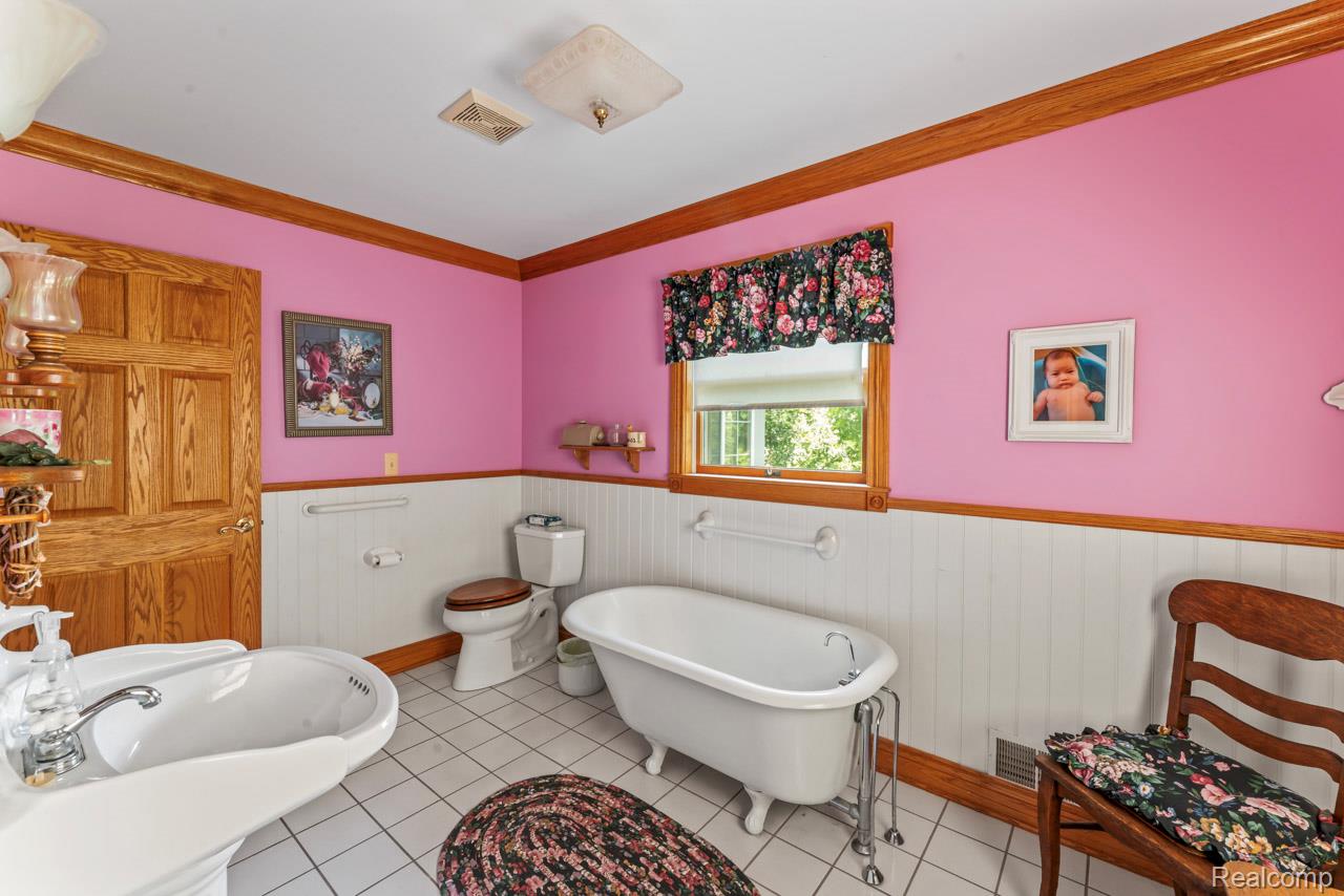 1591 Baldwin Road Lapeer, MI 48446 - Photo 13 of 46 Full bathroom with a freestanding tub, ornamental molding, a wainscoted wall, and light tile patterned floors