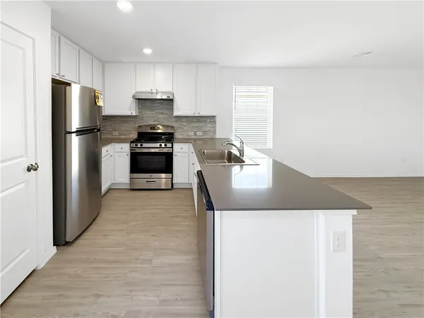 a kitchen with granite countertop a refrigerator and a stove top oven