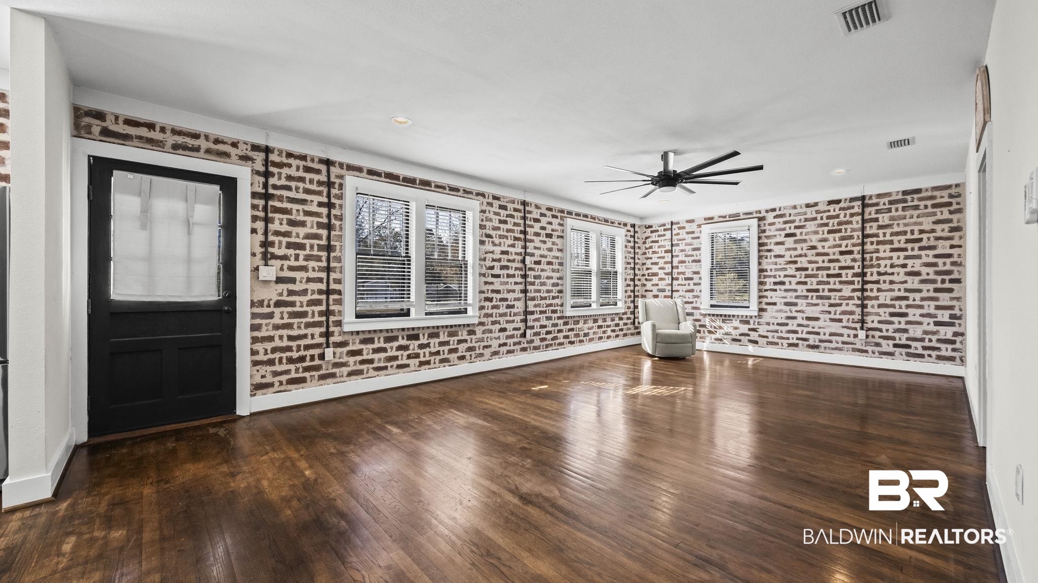 24701 Highway 98 Elberta, AL 36530 - Photo 10 of 32 Unfurnished living room featuring brick wall and dark wood-style floors