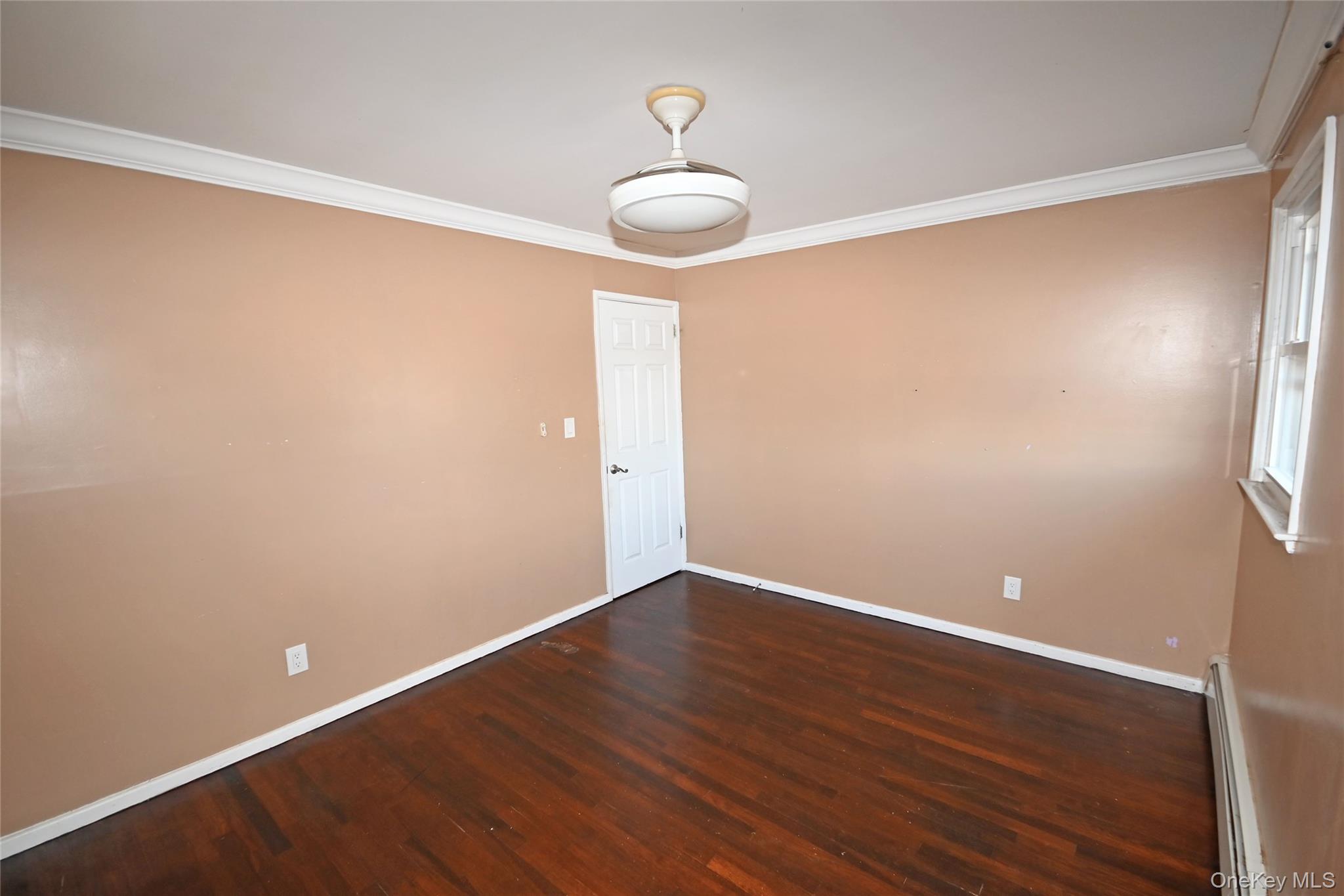 89 Osborne Road West Hempstead, NY 11552 - Photo 10 of 50 Empty room with ornamental molding, dark wood-style floors, and a baseboard heating unit
