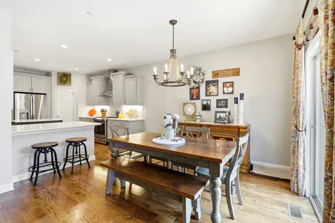 a kitchen with stainless steel appliances granite countertop a table chairs and a refrigerator