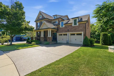 a front view of a house with a garden and trees