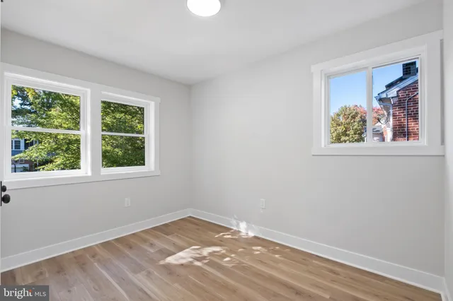 a view of empty room with window and wooden floor