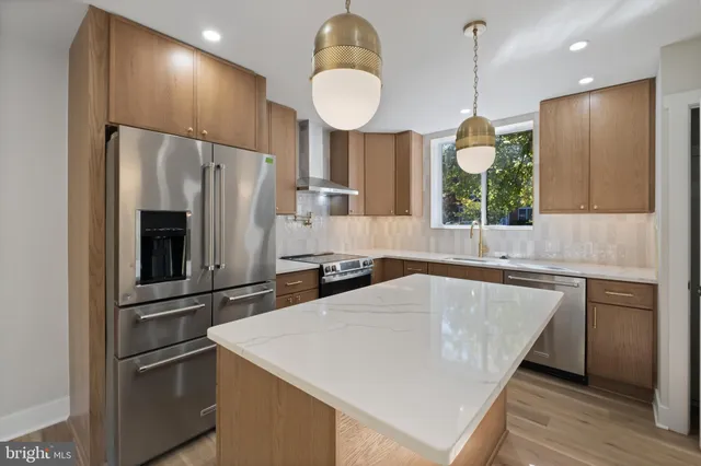 a kitchen with stainless steel appliances a refrigerator a sink a stove and a wooden floors