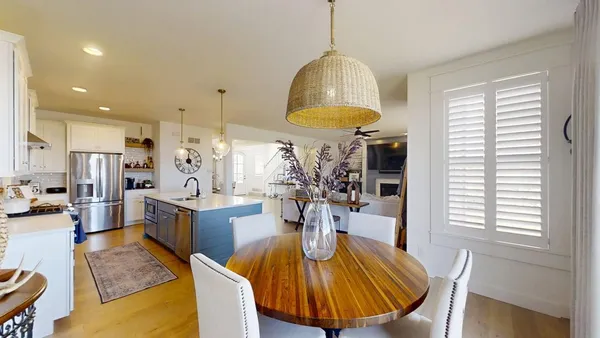 a kitchen with stainless steel appliances a table chairs in it and wooden floors