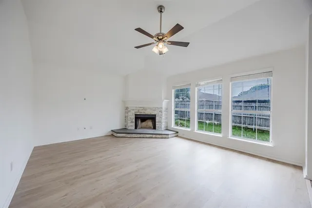 a view of a livingroom with a fireplace a ceiling fan and windows