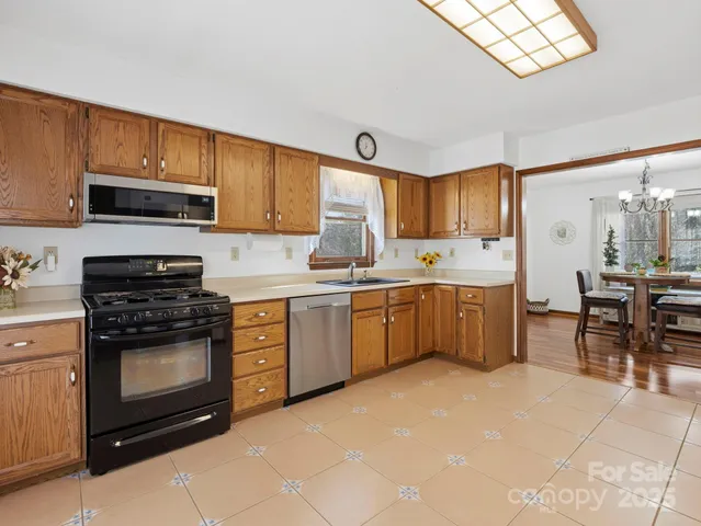 a kitchen with stainless steel appliances a stove top oven a sink a dining table and chairs