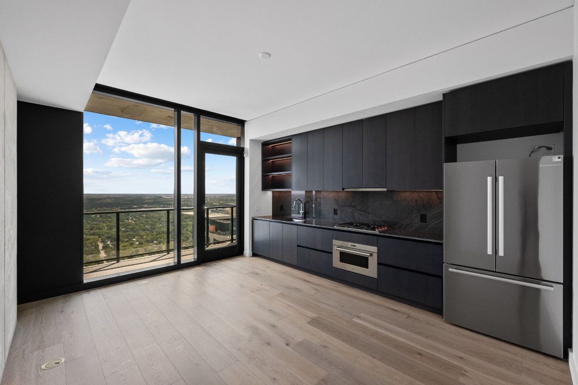 610 Davis Street, Unit 4308 Austin, TX 78701 - Photo 3 of 21 a kitchen with stainless steel appliances a stove top oven a refrigerator and a sink with wooden floor