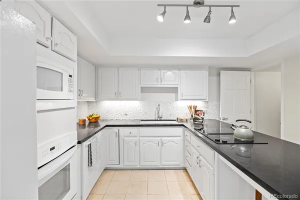 a kitchen with stainless steel appliances granite countertop a sink a stove and white cabinets