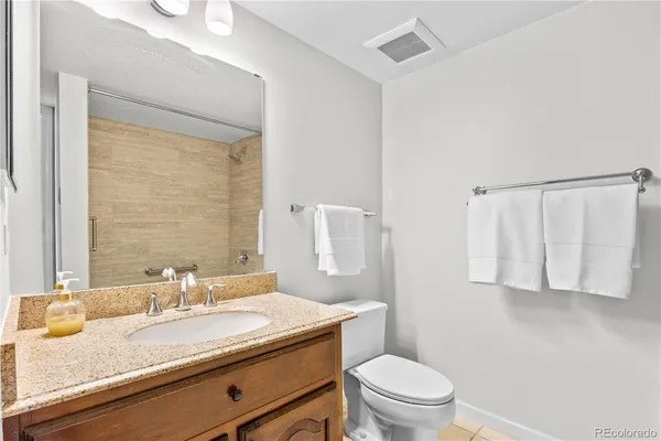 a bathroom with a granite countertop bathtub shower sink vanity and toilet
