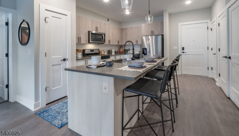 100 Union Street, Unit 353 Elizabeth, NJ 07202 - Photo 19 of 20 a kitchen with stainless steel appliances granite countertop a sink a stove a refrigerator and a dining table with wooden floor