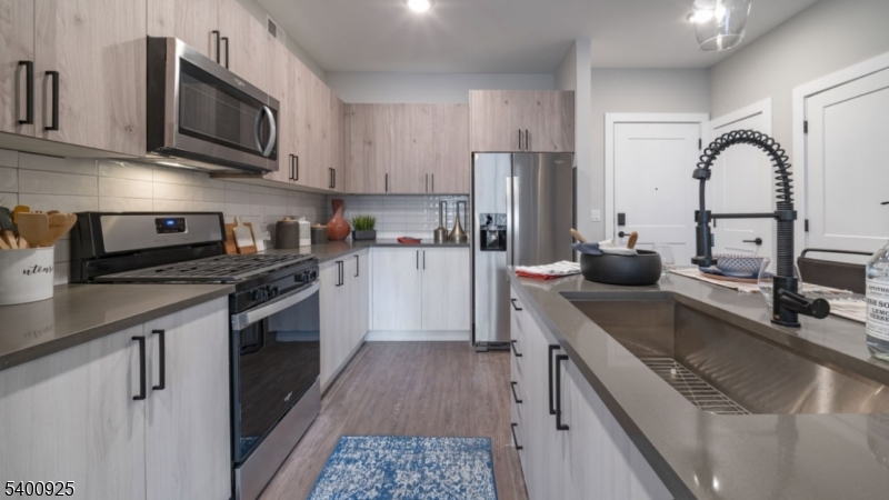 100 Union Street, Unit 353 Elizabeth, NJ 07202 - Photo 20 of 20 a kitchen with stainless steel appliances granite countertop a sink a stove top oven a refrigerator cabinets and a dining table