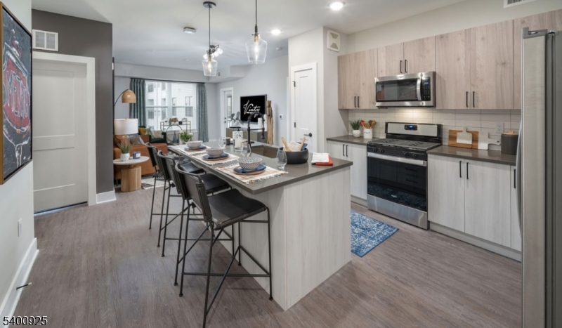 100 Union Street, Unit 353 Elizabeth, NJ 07202 - Photo 2 of 20 a kitchen with stainless steel appliances kitchen island granite countertop a stove top oven a sink dishwasher a dining table and chairs with wooden floor