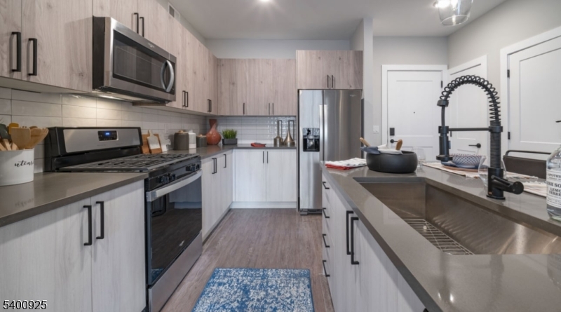 100 Union Street, Unit 353 Elizabeth, NJ 07202 - Photo 9 of 20 a kitchen with stainless steel appliances granite countertop a sink a stove top oven a refrigerator cabinets and a dining table