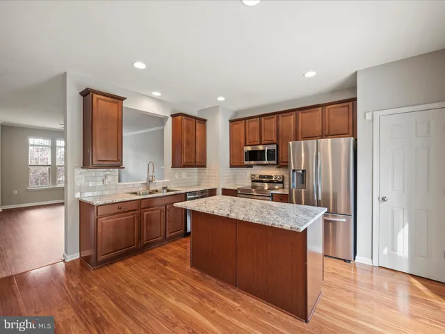 a large kitchen with kitchen island granite countertop wooden floors and stainless steel appliances
