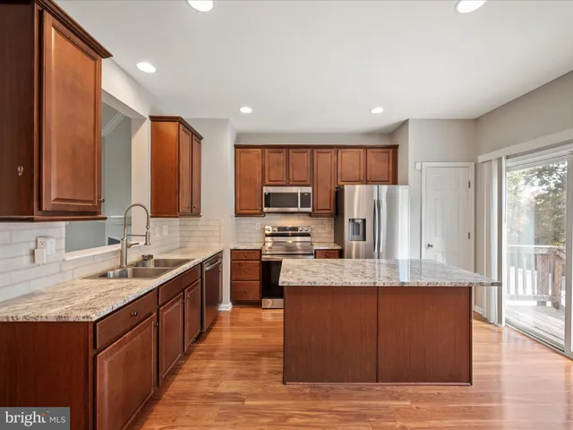 a large kitchen with kitchen island granite countertop a sink refrigerator and cabinets