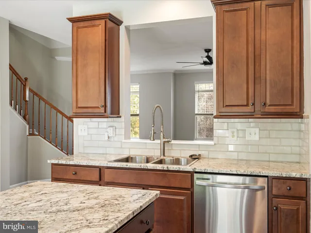 a kitchen with granite countertop a sink a stove and cabinets