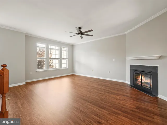 an empty room with wooden floor fireplace and windows