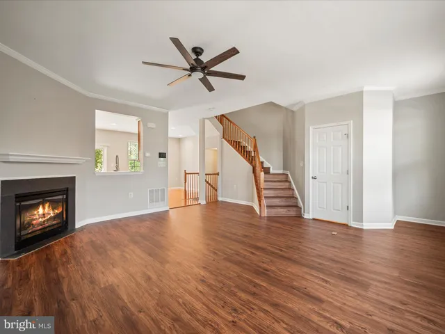 a view of an empty room with wooden floor fireplace and a window
