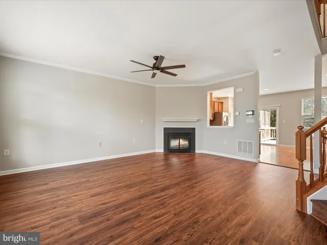 an empty room with wooden floor a ceiling fan and a fireplace