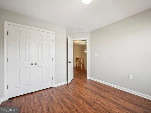 a view of an empty room with wooden floor and closet