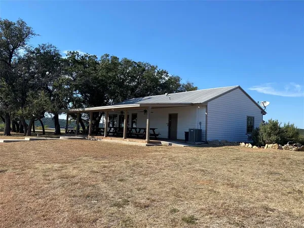 a view of house with outdoor space and trees in the background