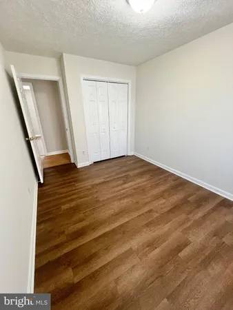 a view of an empty room with wooden floor and stairs