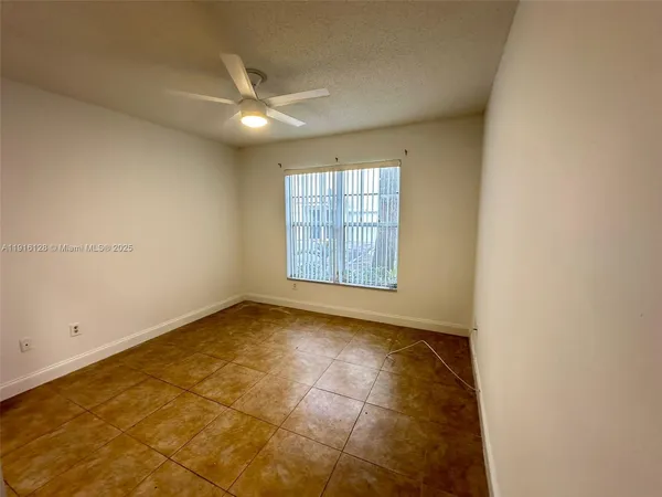 an empty room with windows and chandelier fan