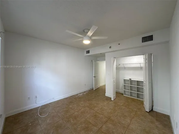 an empty room with closet and a ceiling fan