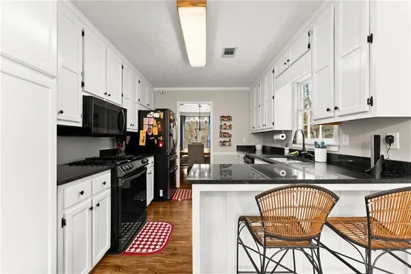 a kitchen with granite countertop a stove top oven a sink a counter space and cabinets