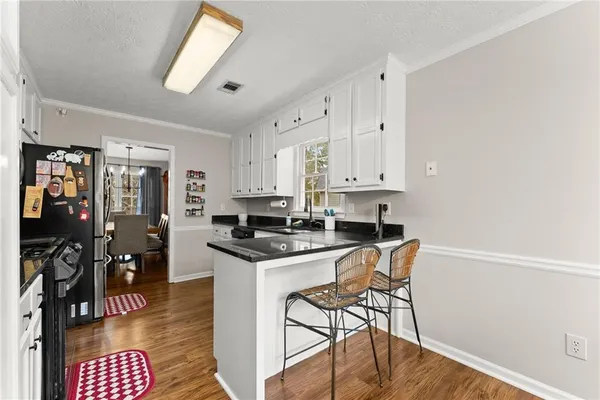 a kitchen with stainless steel appliances granite countertop a stove a refrigerator a sink a dining table and chairs with wooden floor