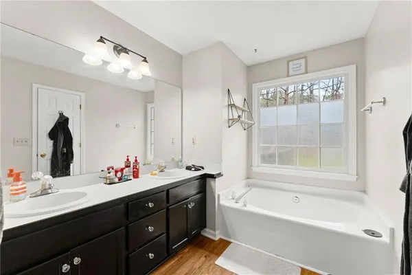 a bathroom with a tub sink double vanity and mirror