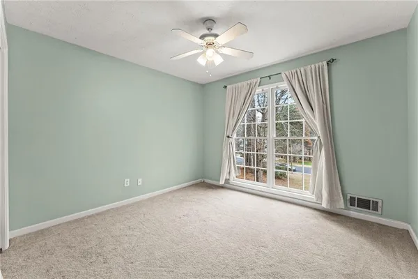 an empty room with windows and ceiling fan