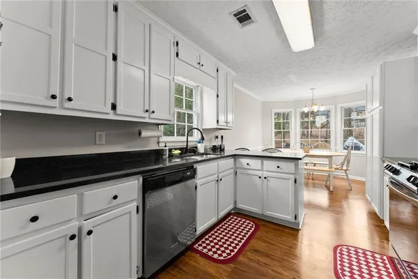 a kitchen with granite countertop white cabinets and black appliances