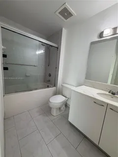 a bathroom with a granite countertop sink mirror vanity and toilet