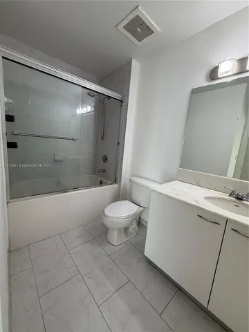 a bathroom with a granite countertop sink mirror vanity and toilet