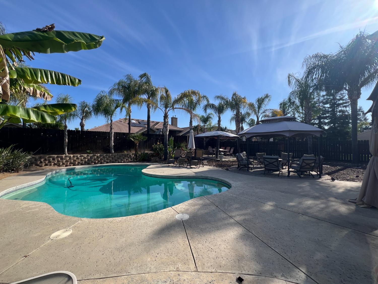2653 Ashcroft Avenue Clovis, CA 93611 - Photo 32 of 45 a view of a swimming pool with a table and chairs under an umbrella