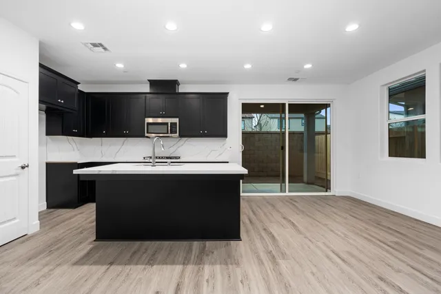 a large kitchen with stainless steel appliances a large counter top a stove and a wooden floors