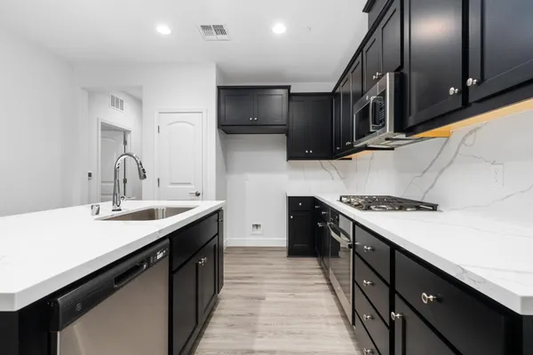 a kitchen with stainless steel appliances a sink stove top oven and cabinets