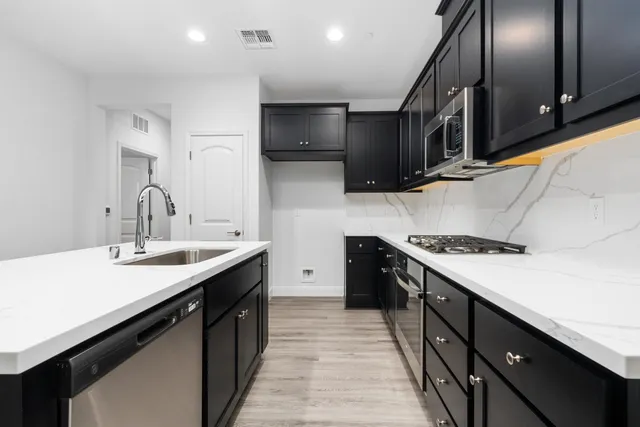 a kitchen with stainless steel appliances a sink stove top oven and cabinets