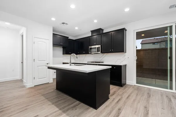 a kitchen with kitchen island granite countertop a sink and a stove top oven with wooden floor