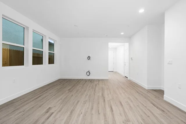 a view of an empty room with wooden floor and windows