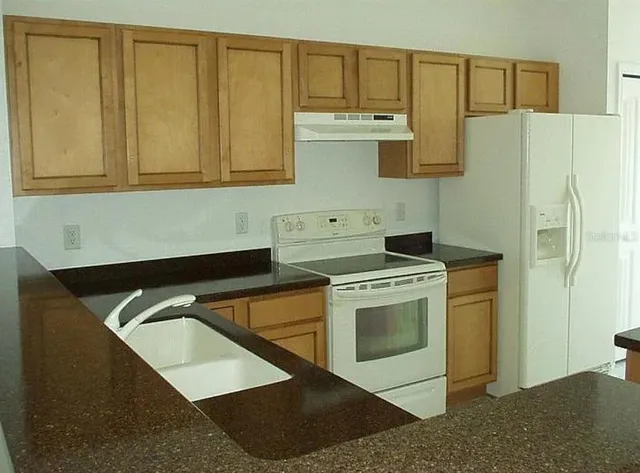 a kitchen with stainless steel appliances granite countertop a sink a stove and a refrigerator