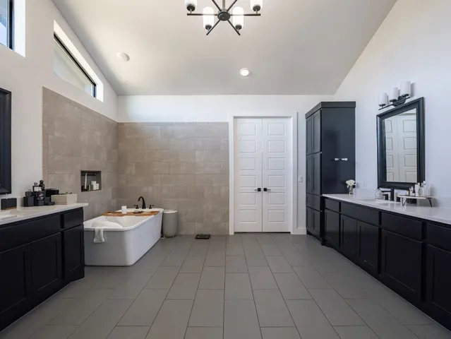 a spacious bathroom with a double vanity sink a mirror and a bathtub