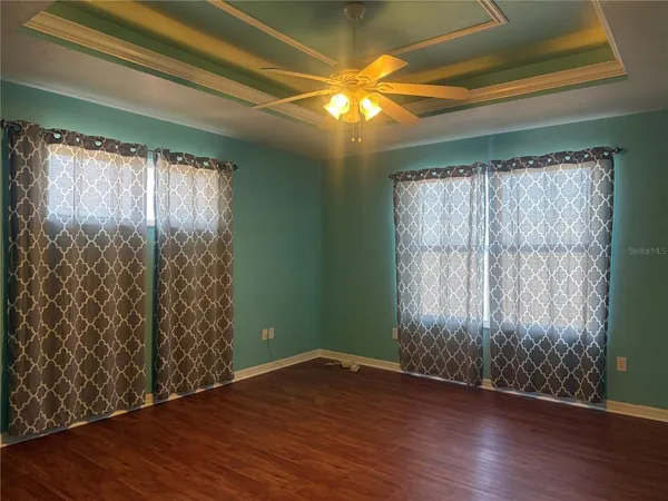a view of empty room with wooden floor and fan
