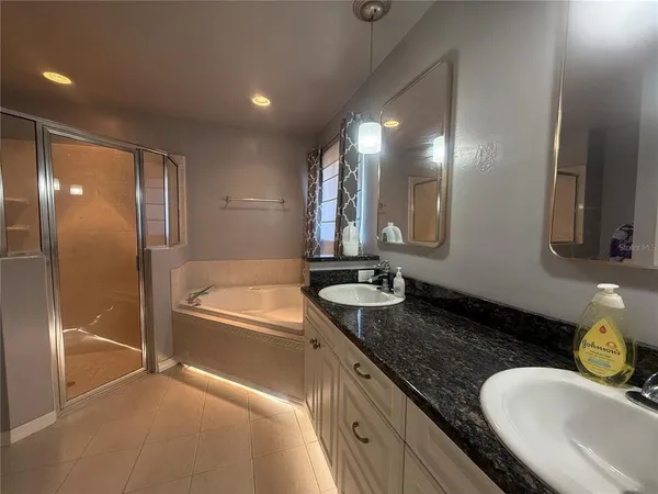 a bathroom with a granite countertop tub sink and mirror