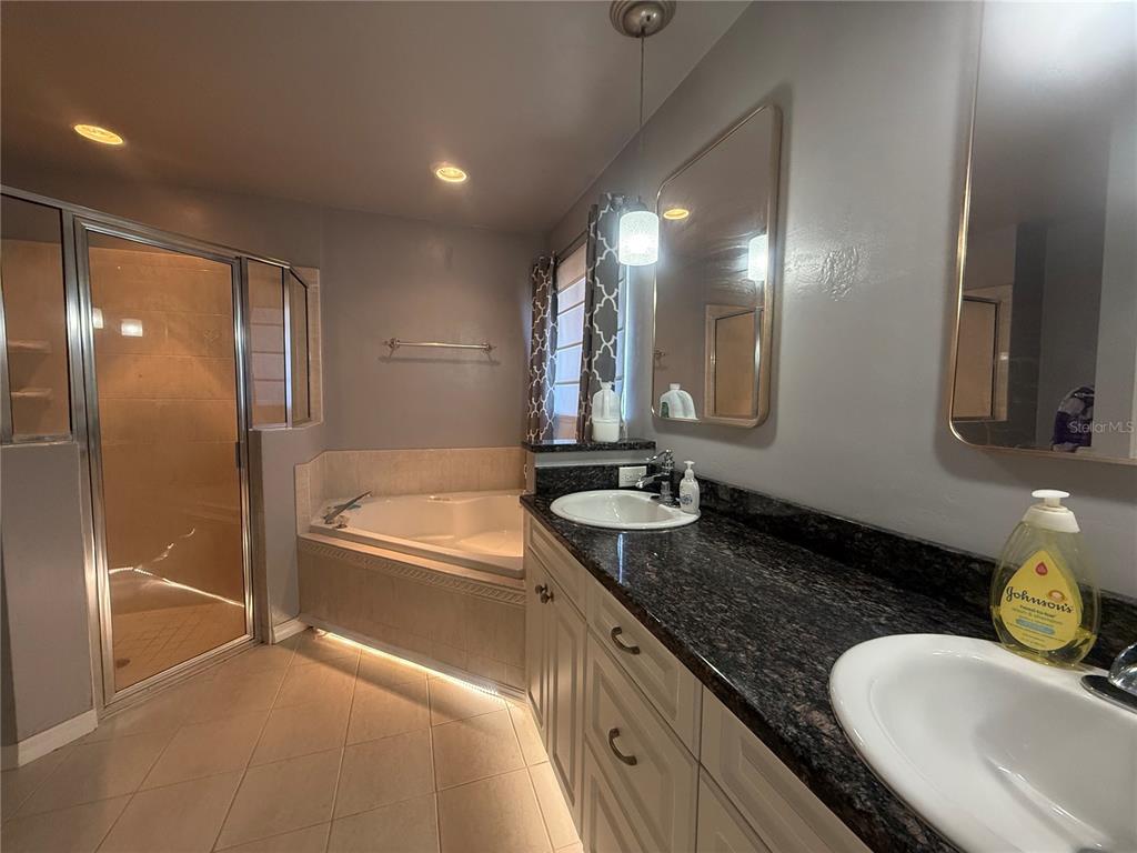 10054 Southwest 98th Avenue Gainesville, FL 32608 - Photo 8 of 14 a bathroom with a granite countertop tub sink and mirror