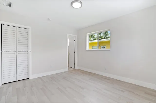 an empty room with wooden floor and window